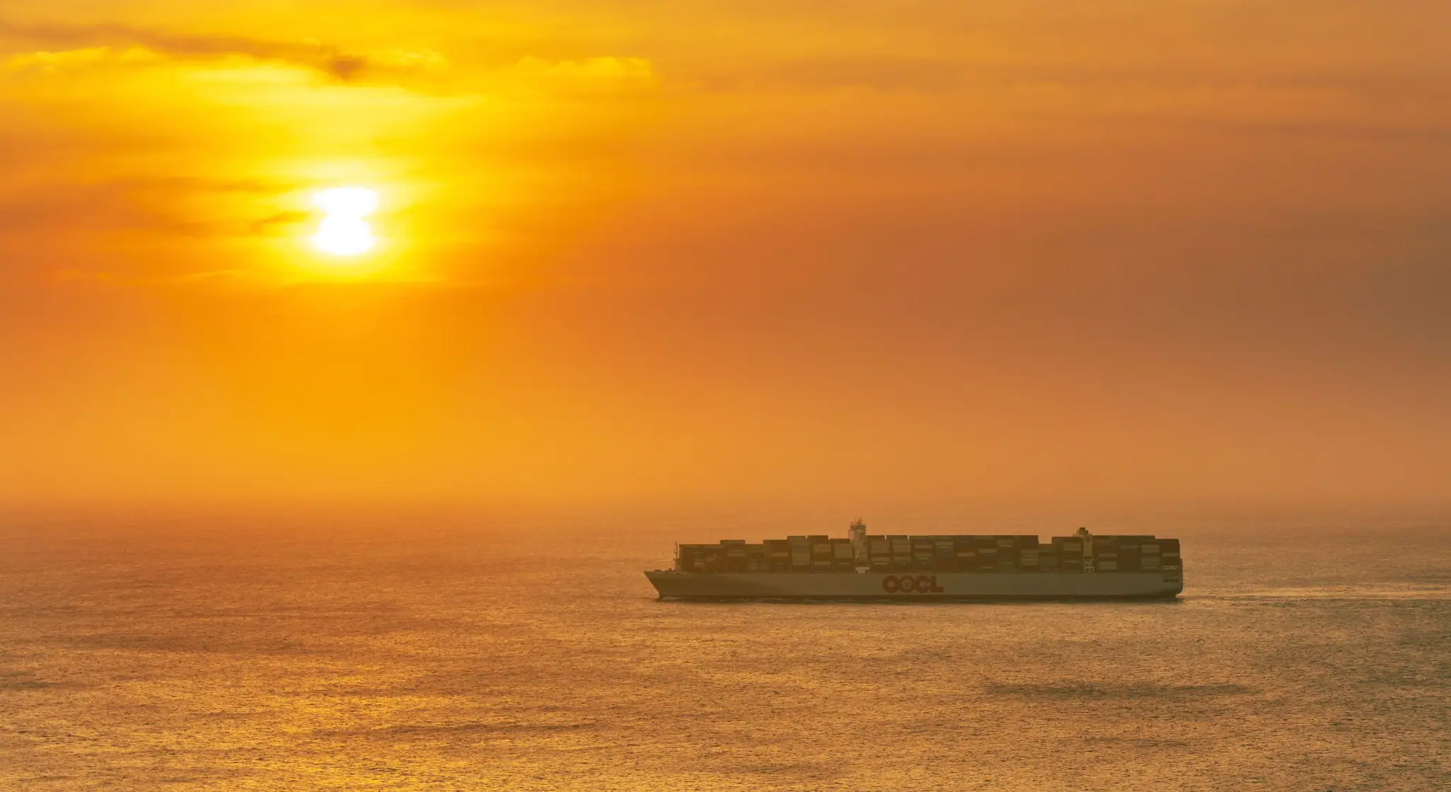 Container ship sailing across the open sea at sunset