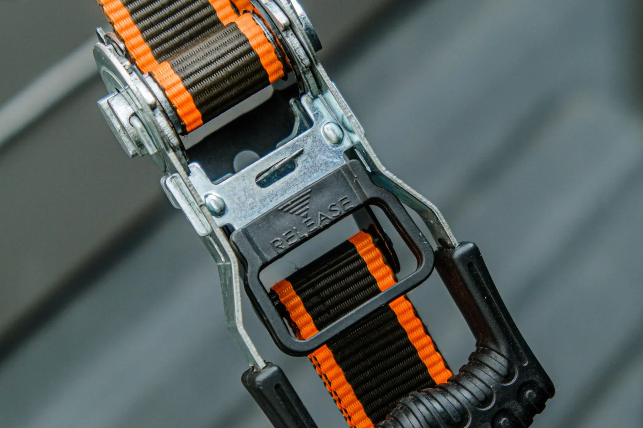 Close-up of an orange ratchet strap buckle pulled tight to secure cargo