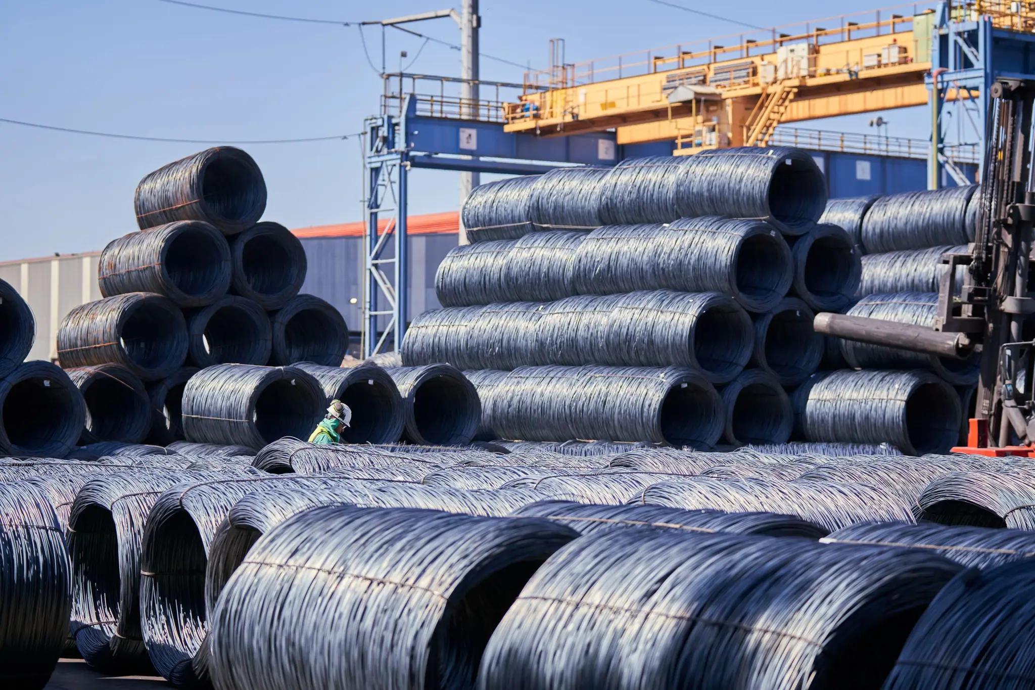 Steel wire coils stacked in a port yard under a gantry crane