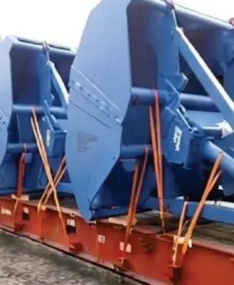Blue steel grab buckets lashed with orange straps on a red flat rack