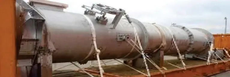 Large steel cylindrical vessel lashed onto a flat rack with straps